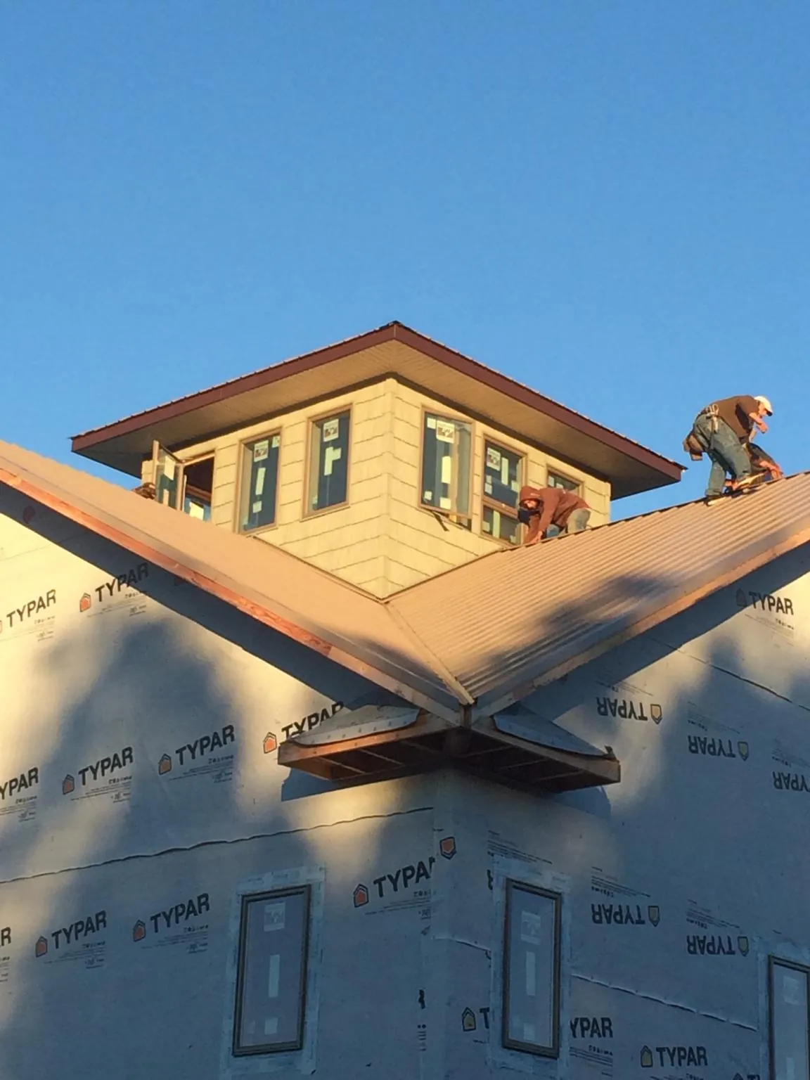 Roofers working around a rooftop cupola on a new metal roof at sunset — Roof Waterproofing in Middlefield by Roofing Brothers
